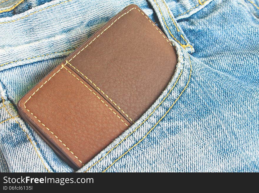 Brown wallet in jeans trousers back pocket, close up texture