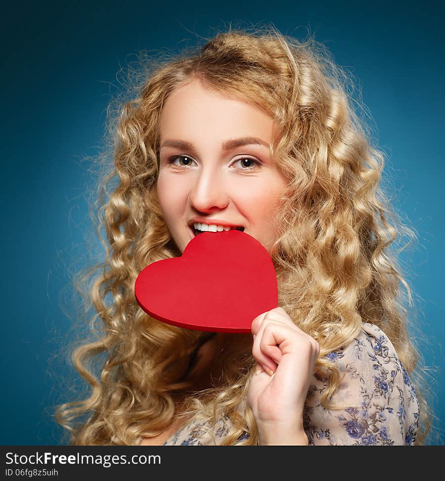 Girl bites heart. Concept of Valentine's Day. Blue background. Girl bites heart. Concept of Valentine's Day. Blue background.