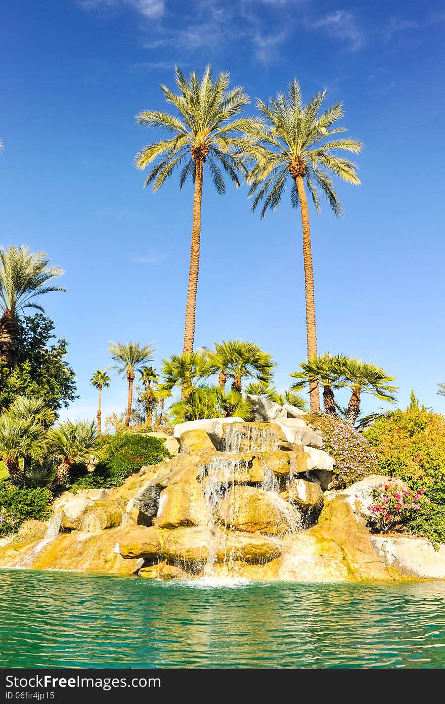 Fountain of water over boulders with row of palm trees. Fountain of water over boulders with row of palm trees