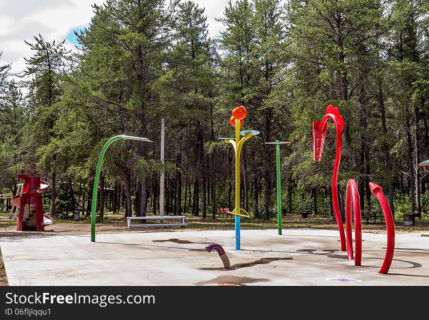 Play structure consisting of a dragon a flower and a slide nestled among the spruce trees at the park. Play structure consisting of a dragon a flower and a slide nestled among the spruce trees at the park