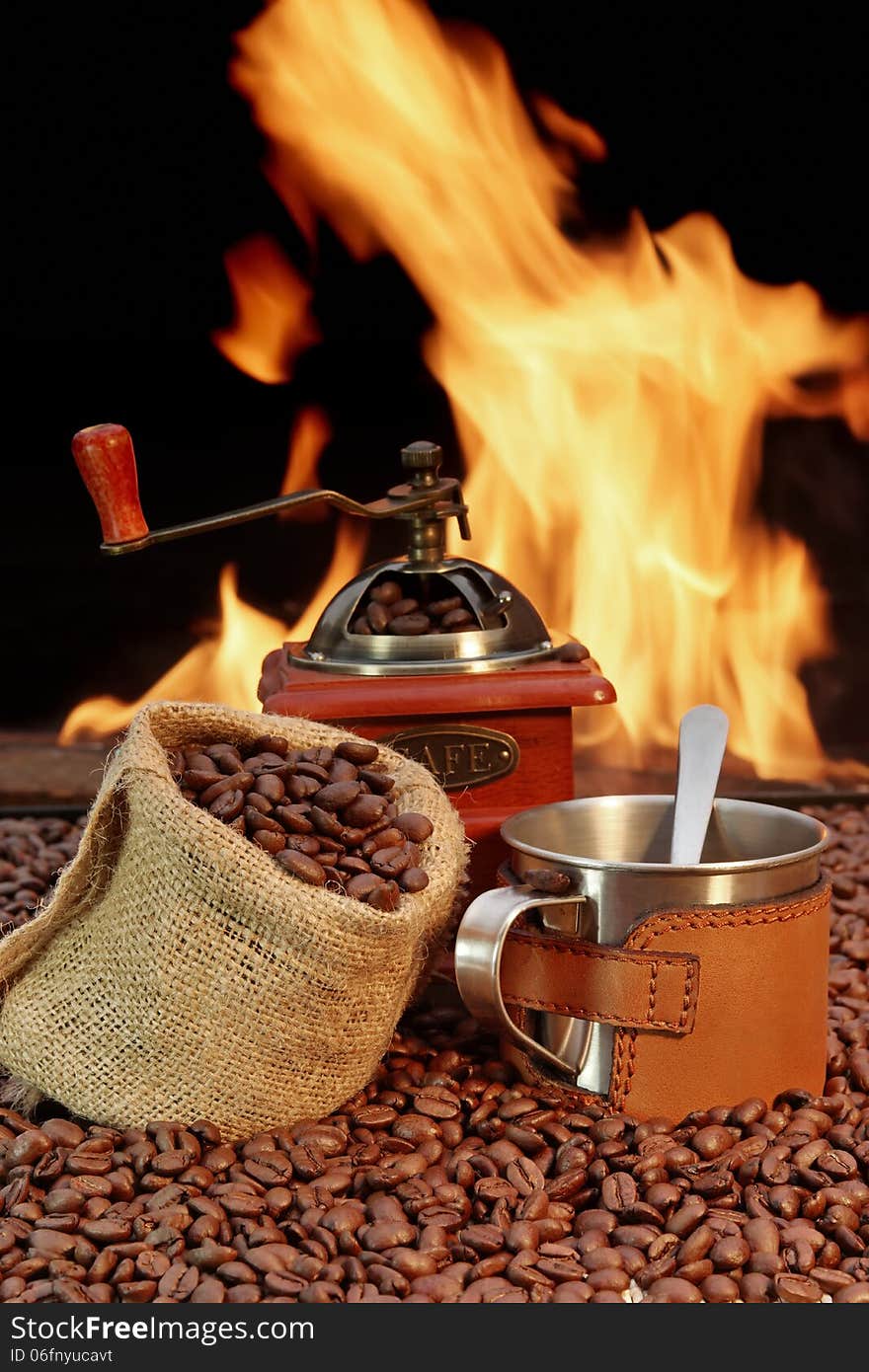 Coffee Mug and, jute sack with coffee beans and grinder on a background of fire. Coffee Mug and, jute sack with coffee beans and grinder on a background of fire