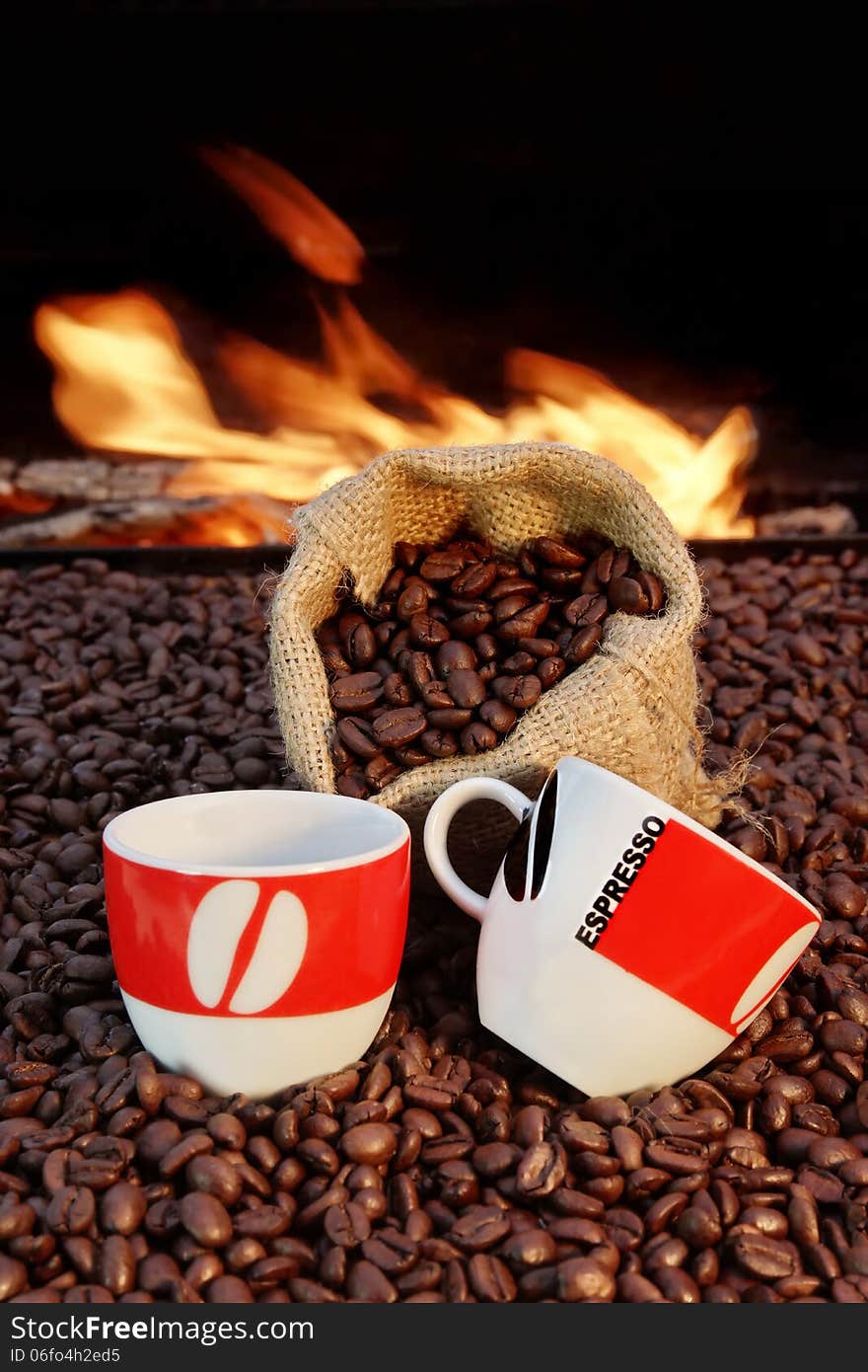 Two ceramic cups and a jute sack with coffee beans on a background of fire. Two ceramic cups and a jute sack with coffee beans on a background of fire