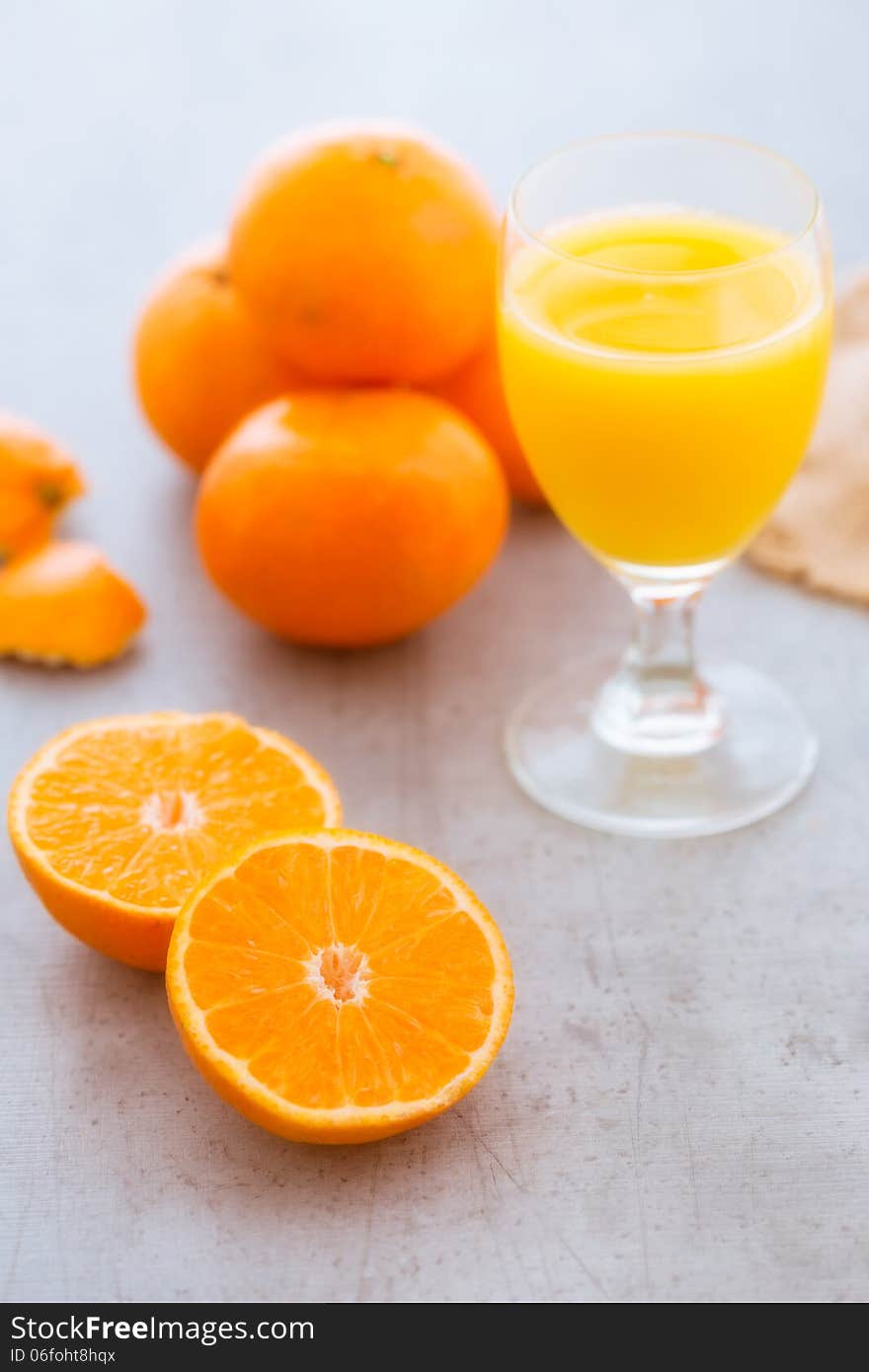 Squeezing a glass of fresh orange juice with a halved fresh orange in the foreground showing the succulent juicy pulp with a glass of healthy juice and whole fruit behind