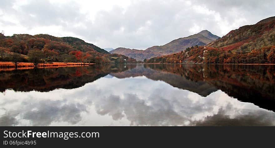 Reflections of Snowdonia, Llyn Gwynant reflecting mountains and trees high lighted by the sun rise, Snowdon, Snowdonia, Wales. The lake was like a mirror with no breeze at all. Reflections of Snowdonia, Llyn Gwynant reflecting mountains and trees high lighted by the sun rise, Snowdon, Snowdonia, Wales. The lake was like a mirror with no breeze at all.