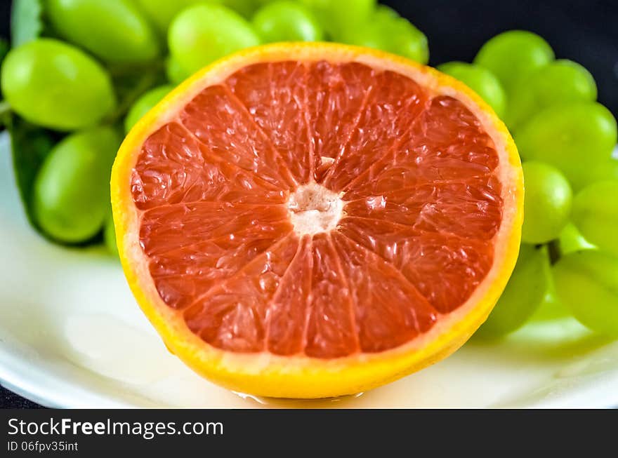 Freshly cut grapefruit with green grapes in the background.