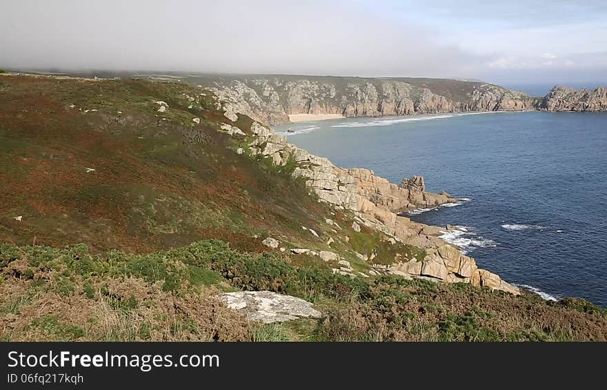 Coast of Cornwall England in autumn with mist and blue sky near the Minack Theatre and Porthcurno