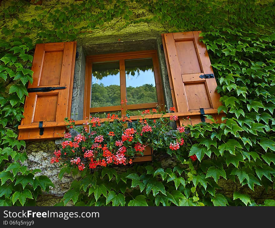 Typical Italian creative window with wooden shutters and beautiful colorful flowers