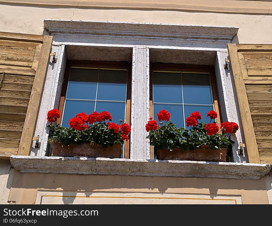 Typical Italian creative window with wooden shutters and beautiful colorful flowers