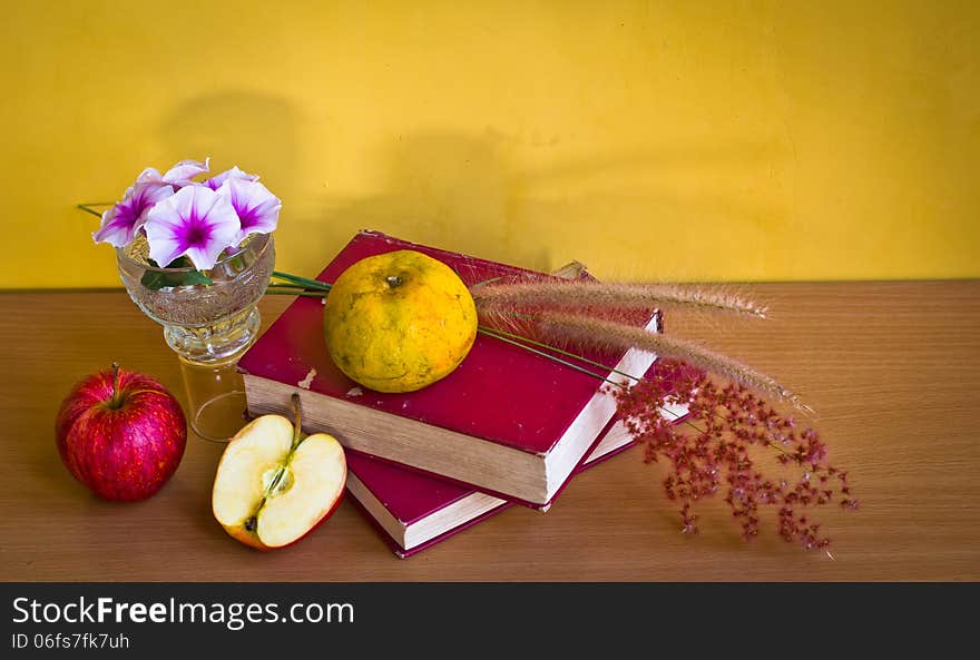 Antique book with wild flower and fruit on table with yellow wall. Antique book with wild flower and fruit on table with yellow wall