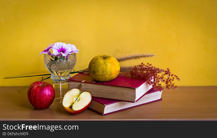 Antique book with flower and fruit on table with yellow background