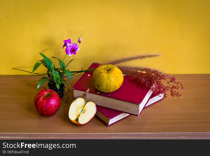 Antique book with flower and fruit on table with yellow background