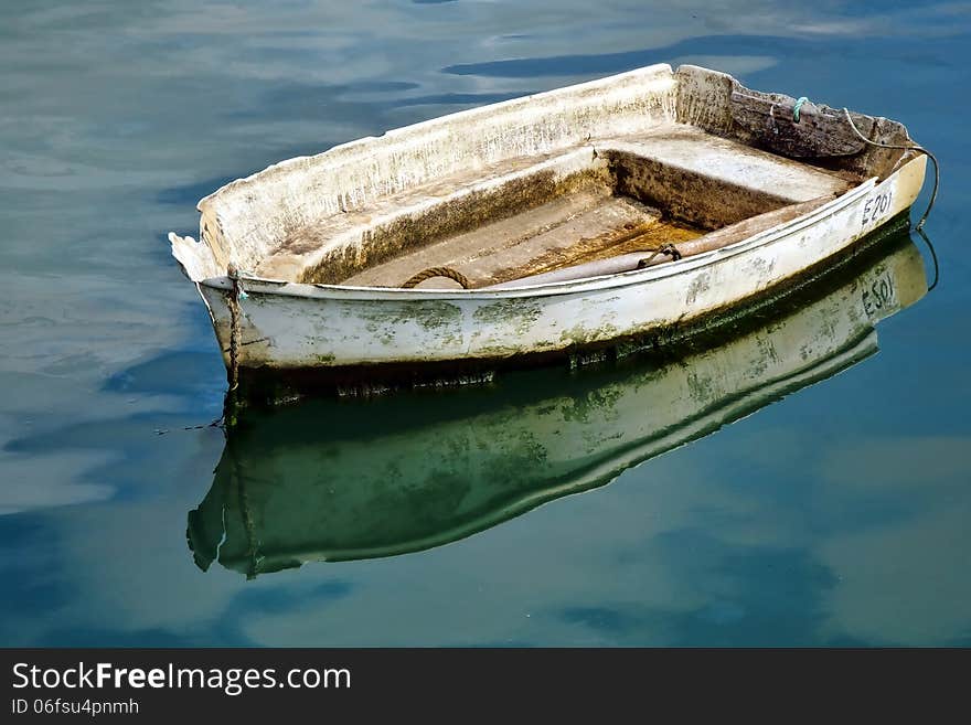 Battered old boat and reflections inside a harbour. Battered old boat and reflections inside a harbour.