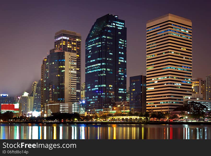 Night cityscape, office buildings and apartments in Thailand at dusk. View from public park.