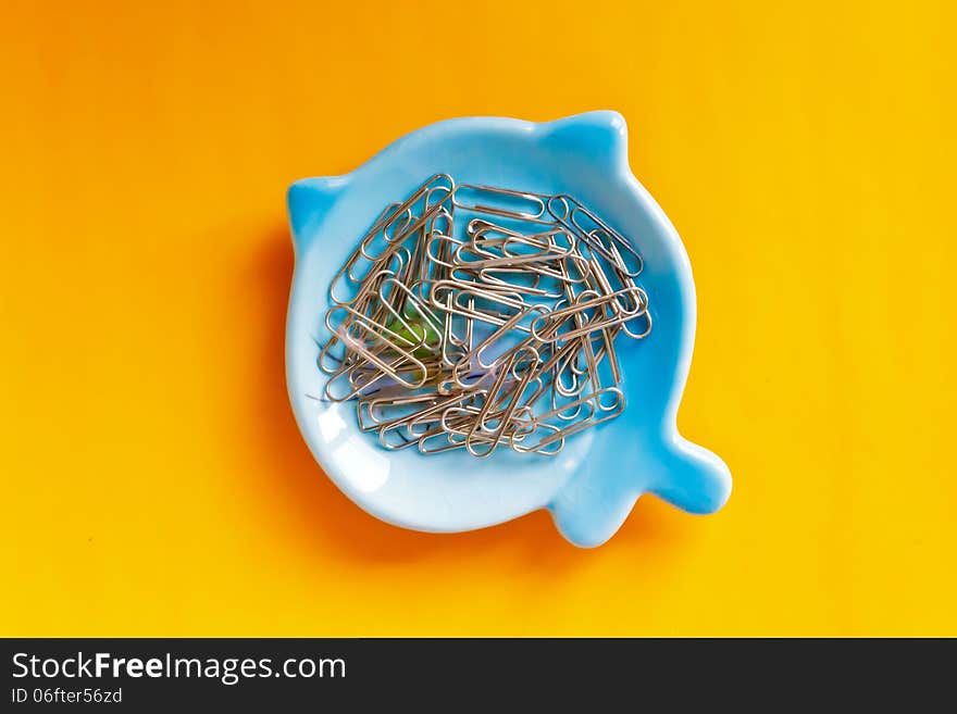 Paper clip on blue plate and orange background