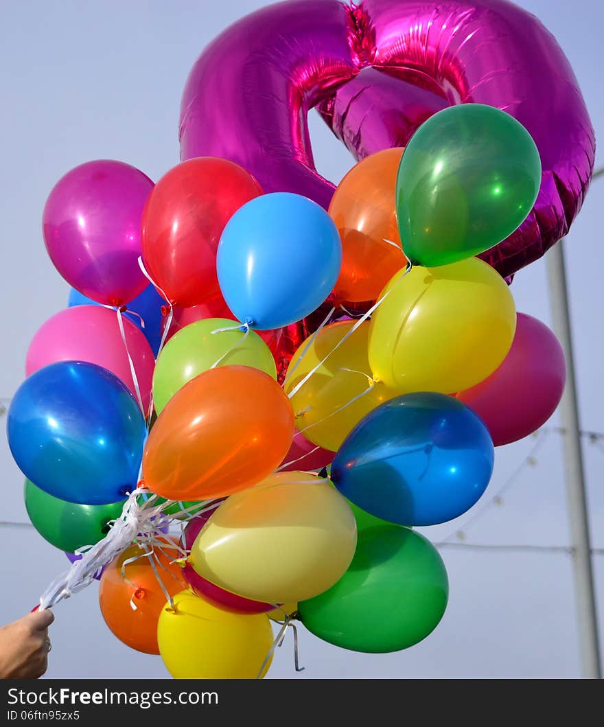 Large group of brightly coloured balloons against a blue sky