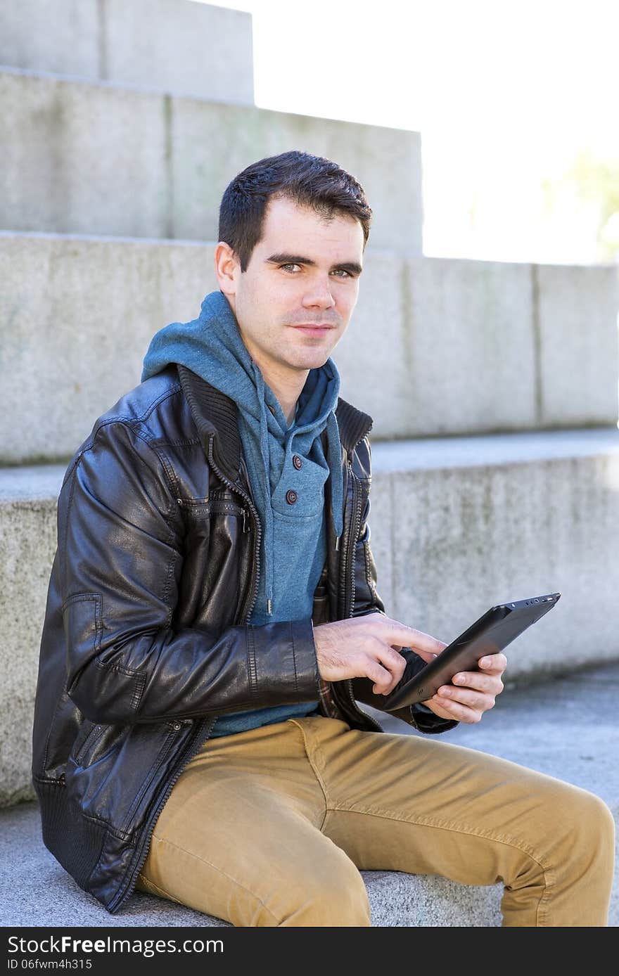 Man with tablet computer looking at the camera, outdoor.