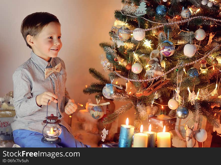 In the snow with lights garlands at home boy and Christmas tree