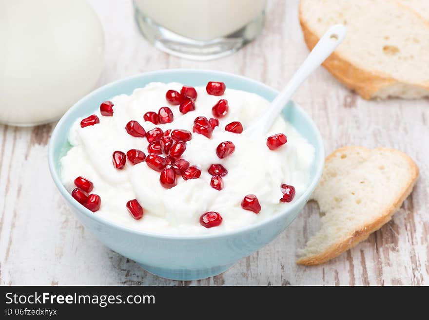 Homemade yogurt with pomegranate, milk and bread, top view, close-up