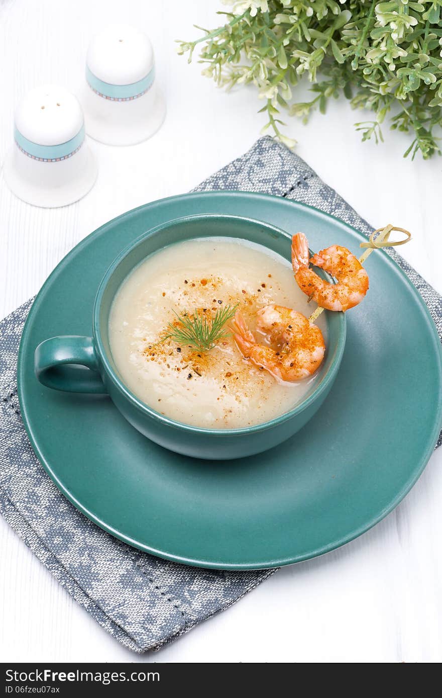 Potato cream soup with glazed shrimp on a skewer