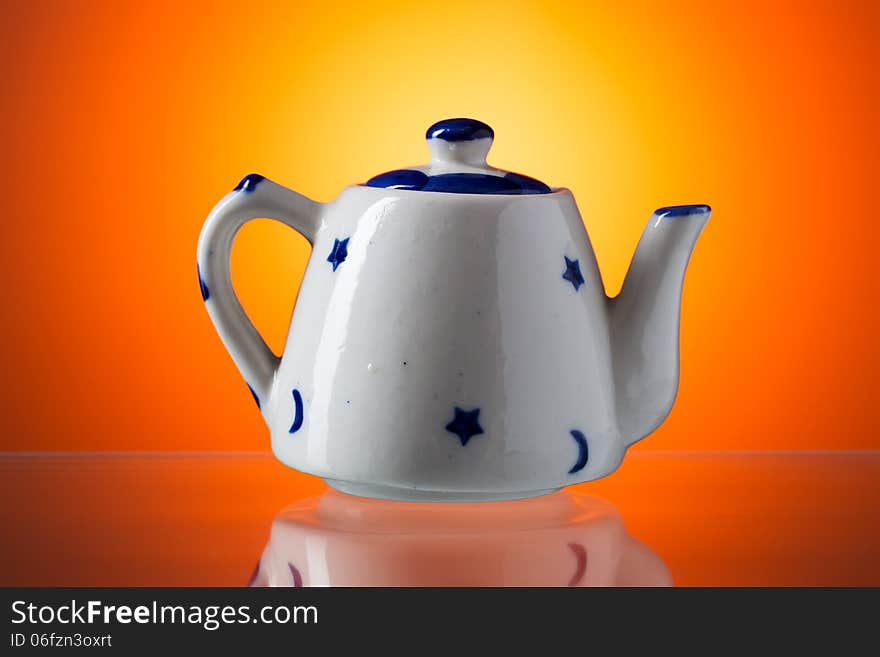 Ceramic teapot with blue stars on orange background.