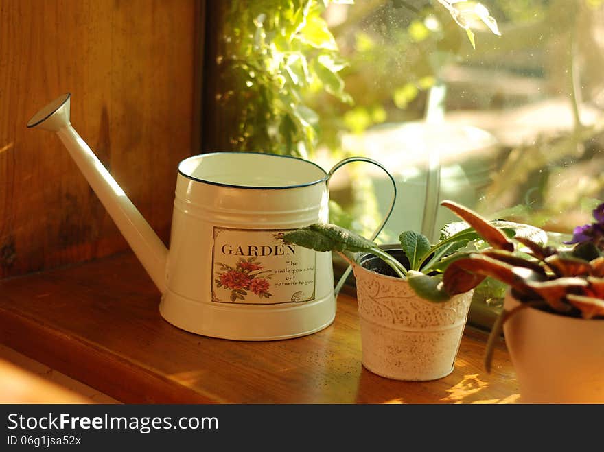 Watering can on the windowsill on a sunny summer day. Watering can on the windowsill on a sunny summer day