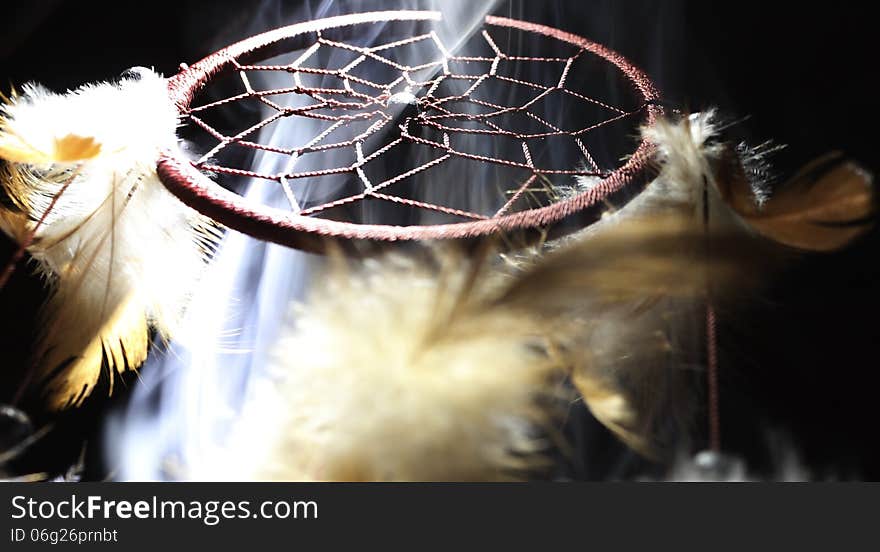 Dreamcatcher illuminated from a low angle smoke filled using an incense burner with a black background. Dreamcatcher illuminated from a low angle smoke filled using an incense burner with a black background.