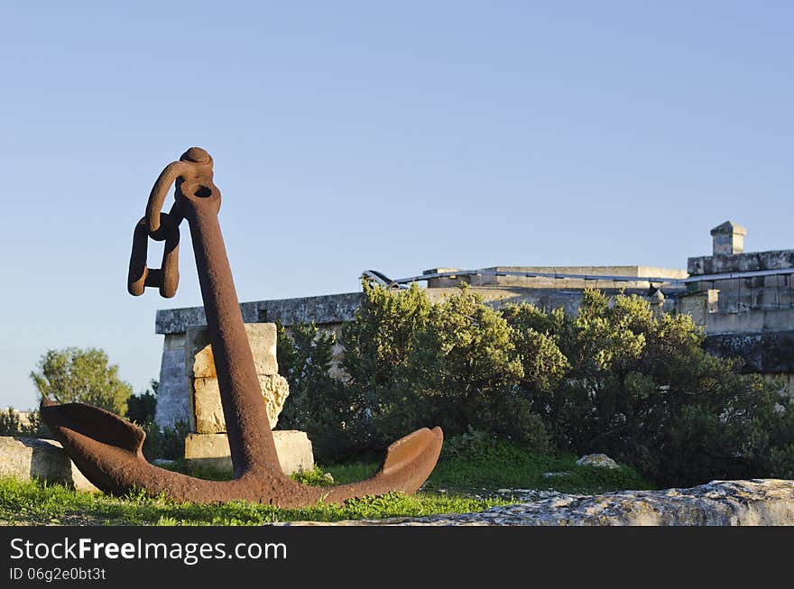 A large rusted anchor resting against some stones