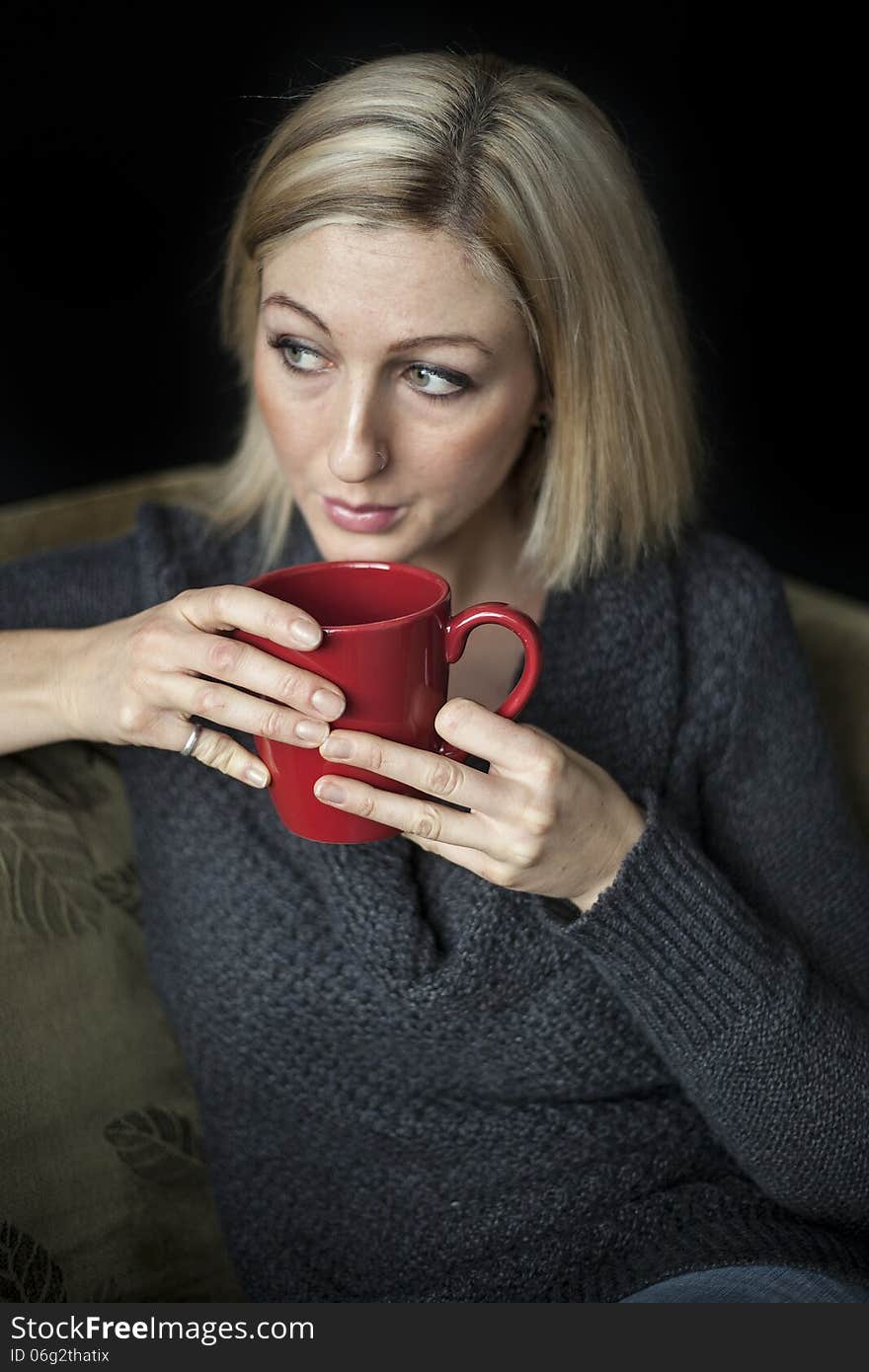 Portrait of a blonde woman with blue eyes holding a red coffee cup. Portrait of a blonde woman with blue eyes holding a red coffee cup.