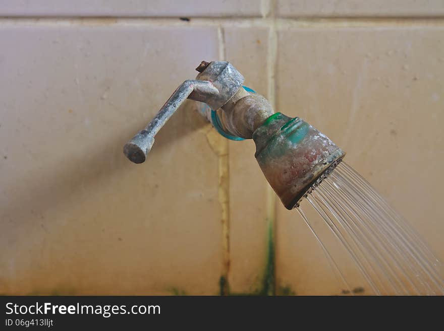 Old rusty faucet on the tile wall in bathroom