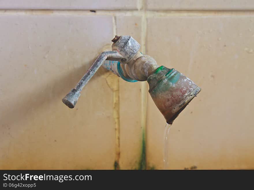 Old rusty faucet on the tile wall in bathroom