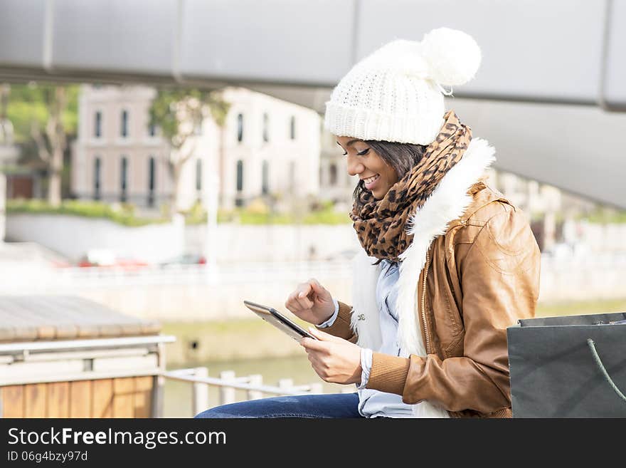 Smiling girl using tablet computer in public space. Smiling girl using tablet computer in public space.