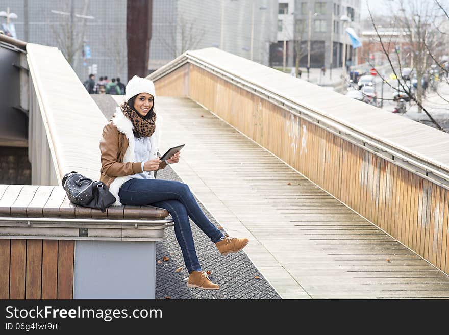 Smiling student using tablet computer in the street.