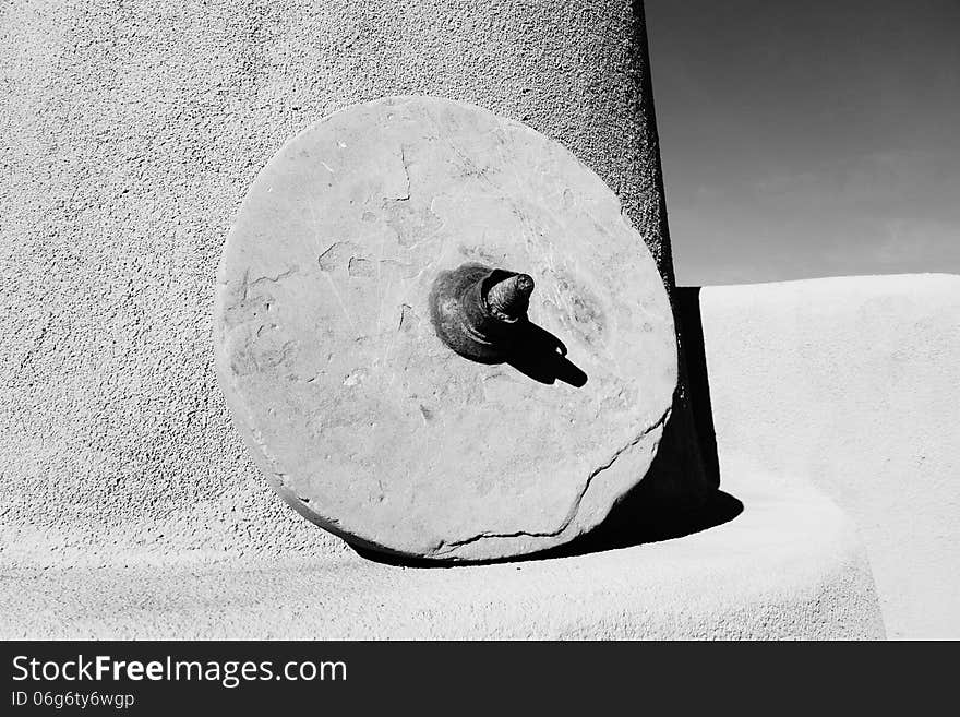 A picture of a antique grinding stone sitting on a mantel on a patio.