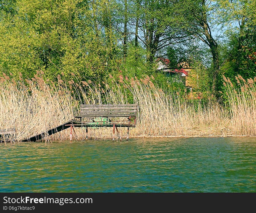 The old bench and trees over Lake Powidzkie in the spring season. The old bench and trees over Lake Powidzkie in the spring season.