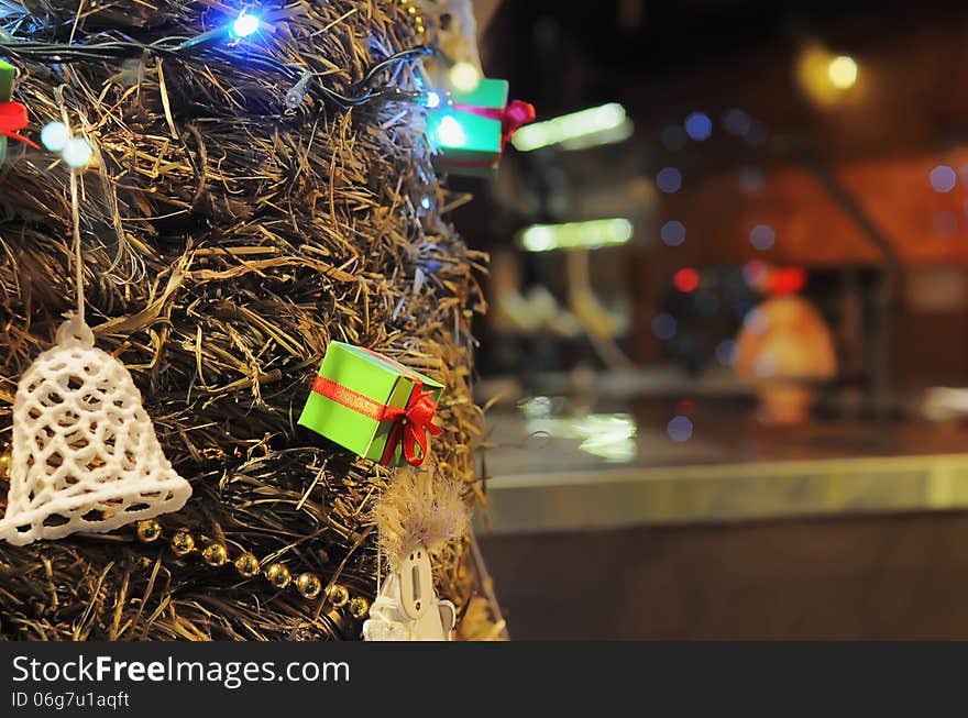 Green gift box with garland,lights and bell on a Christmas tree