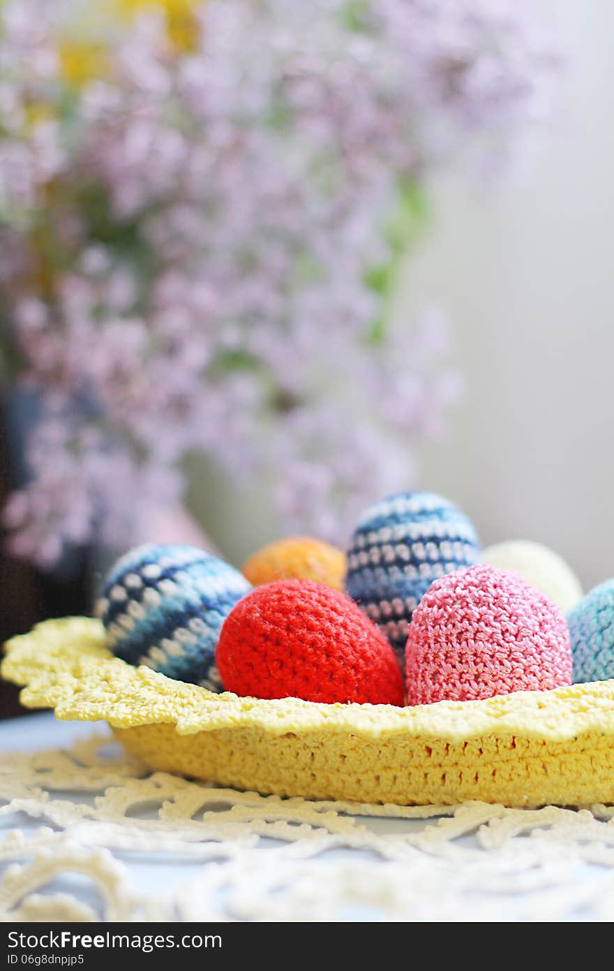 Basket of handmade knitted Easter eggs and lilac flower