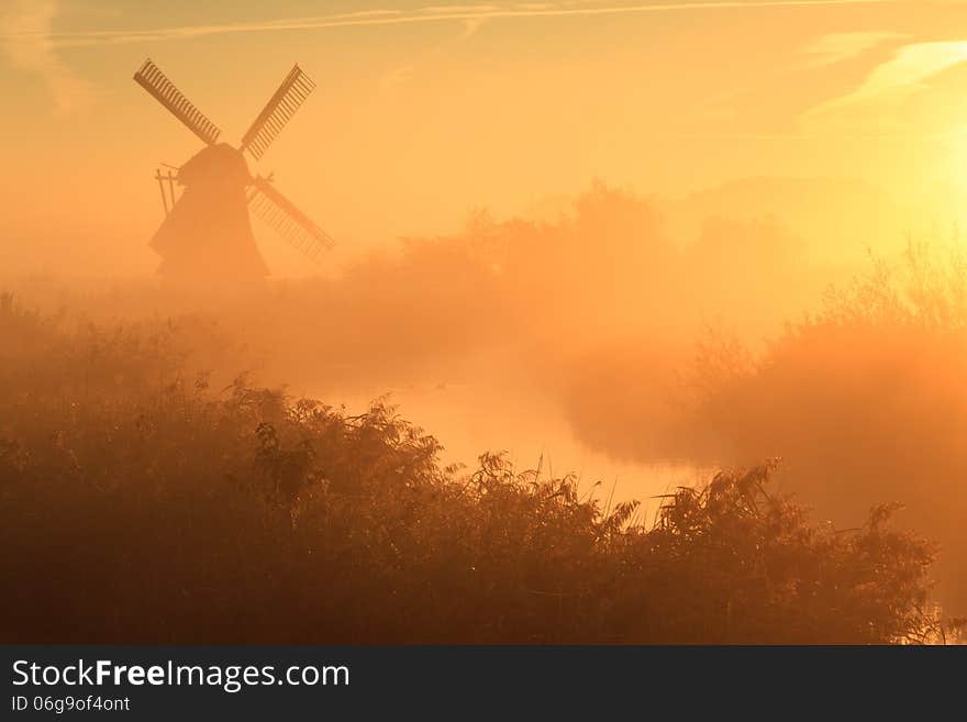 Foggy and colorful autumn sunrise at a traditional, Dutch windmill.