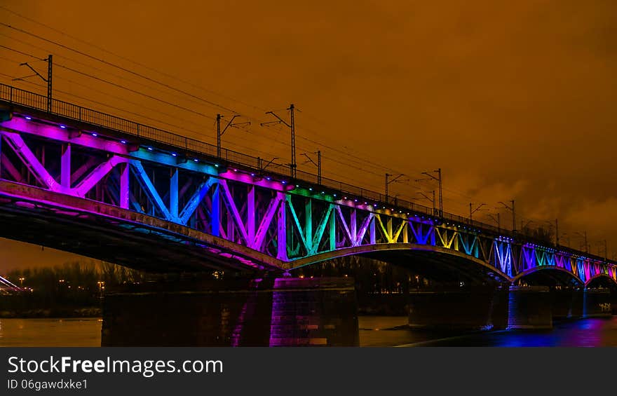 Colorfully illuminated railway bridge over Vistula river in Warsaw, Poland.