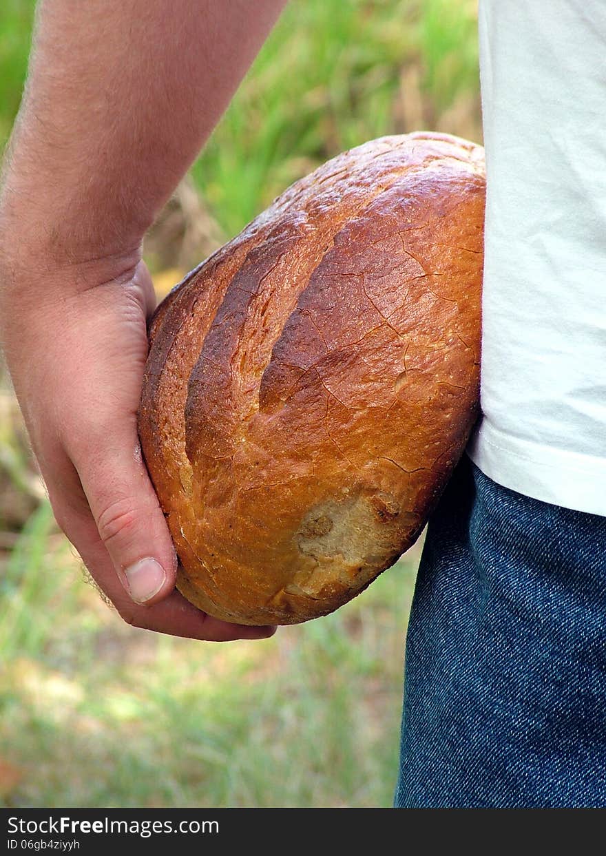 A man holds in his hands a loaf of bread. A man holds in his hands a loaf of bread.