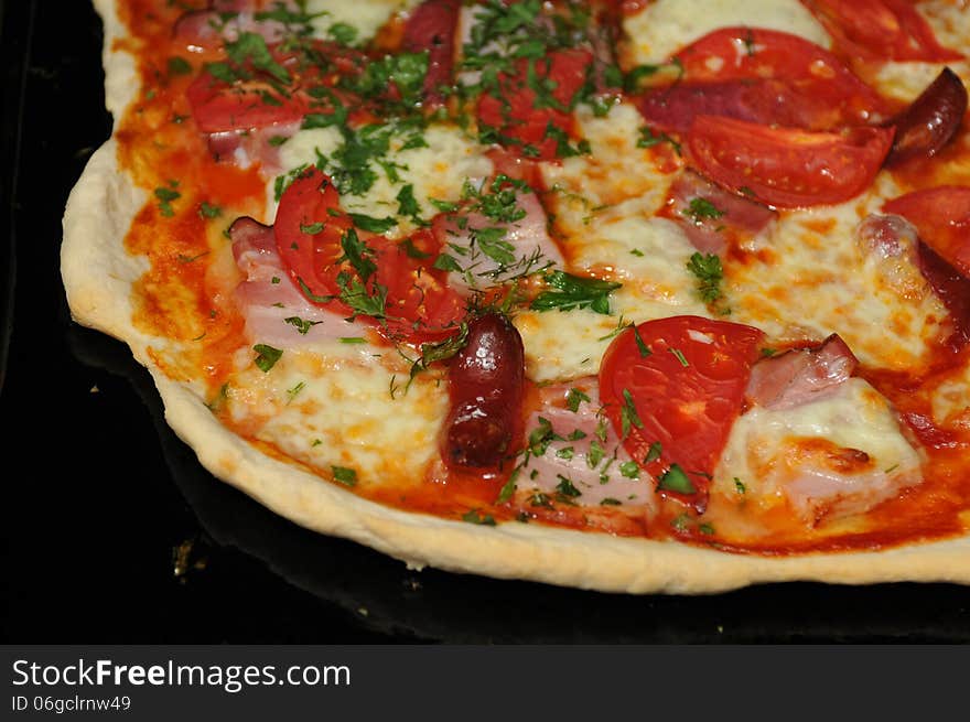 Piece of pizza closeup on black baking tray