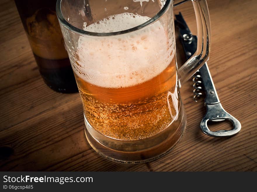 A mug and a bottle of beer with froth and slight spill. A mug and a bottle of beer with froth and slight spill.