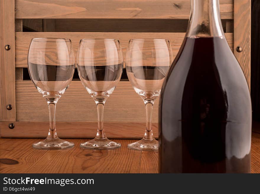 Bottle of red wine and three empty glasses on a wooden backgroung. Bottle of red wine and three empty glasses on a wooden backgroung