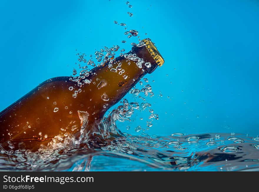 Image of beer bottle in water on a blue background