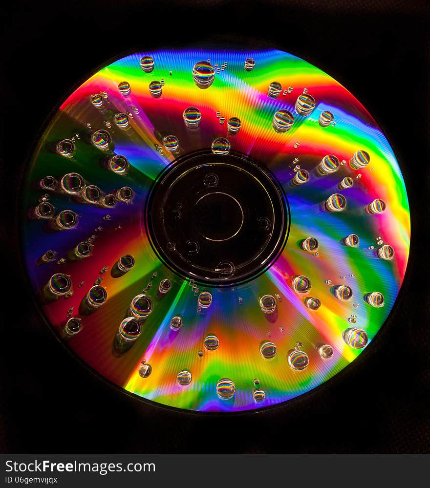 Closeup of water drops on a multicolored surface of CD. Closeup of water drops on a multicolored surface of CD