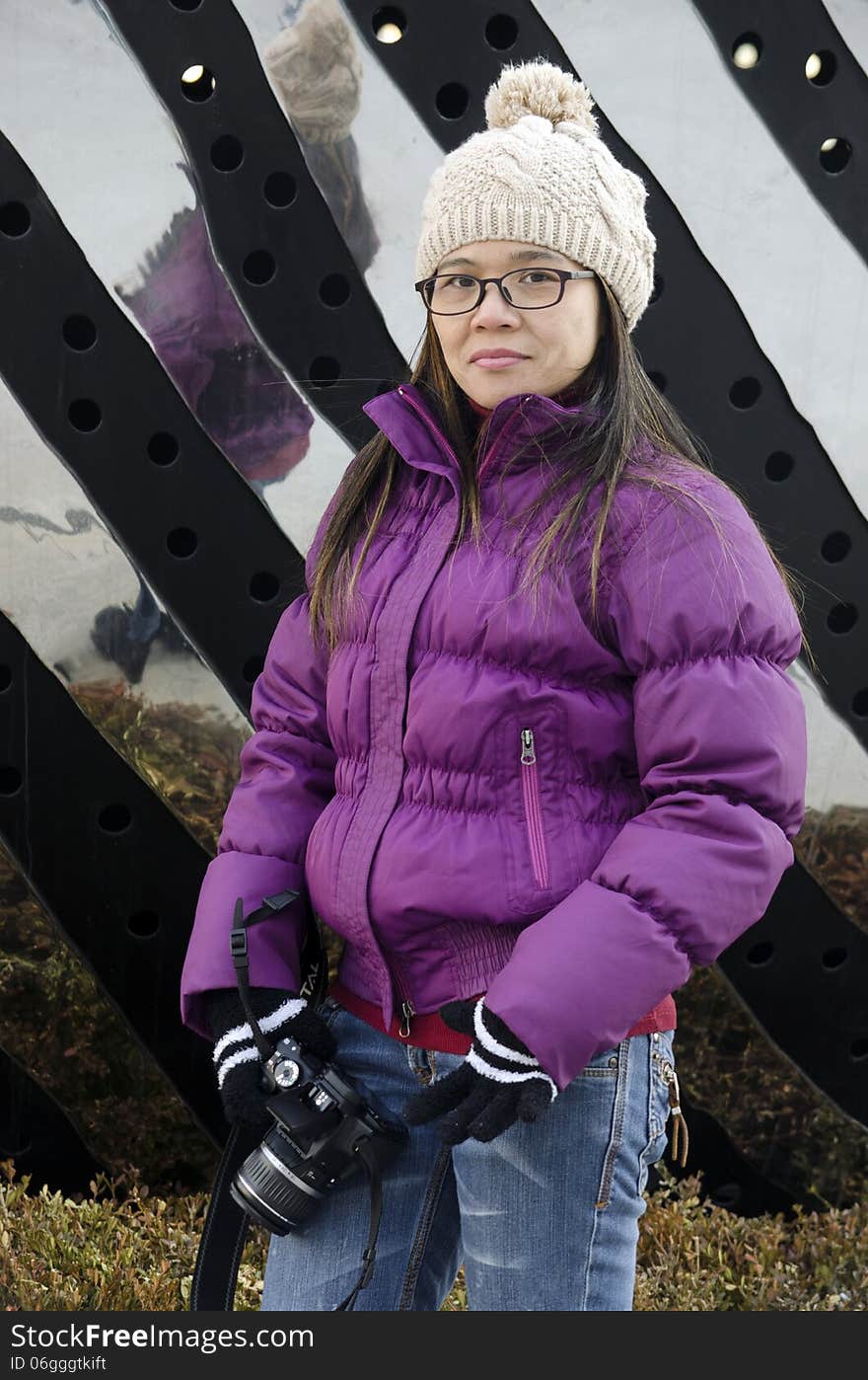 A young Asian woman poses in front of a local sculpture. A young Asian woman poses in front of a local sculpture.