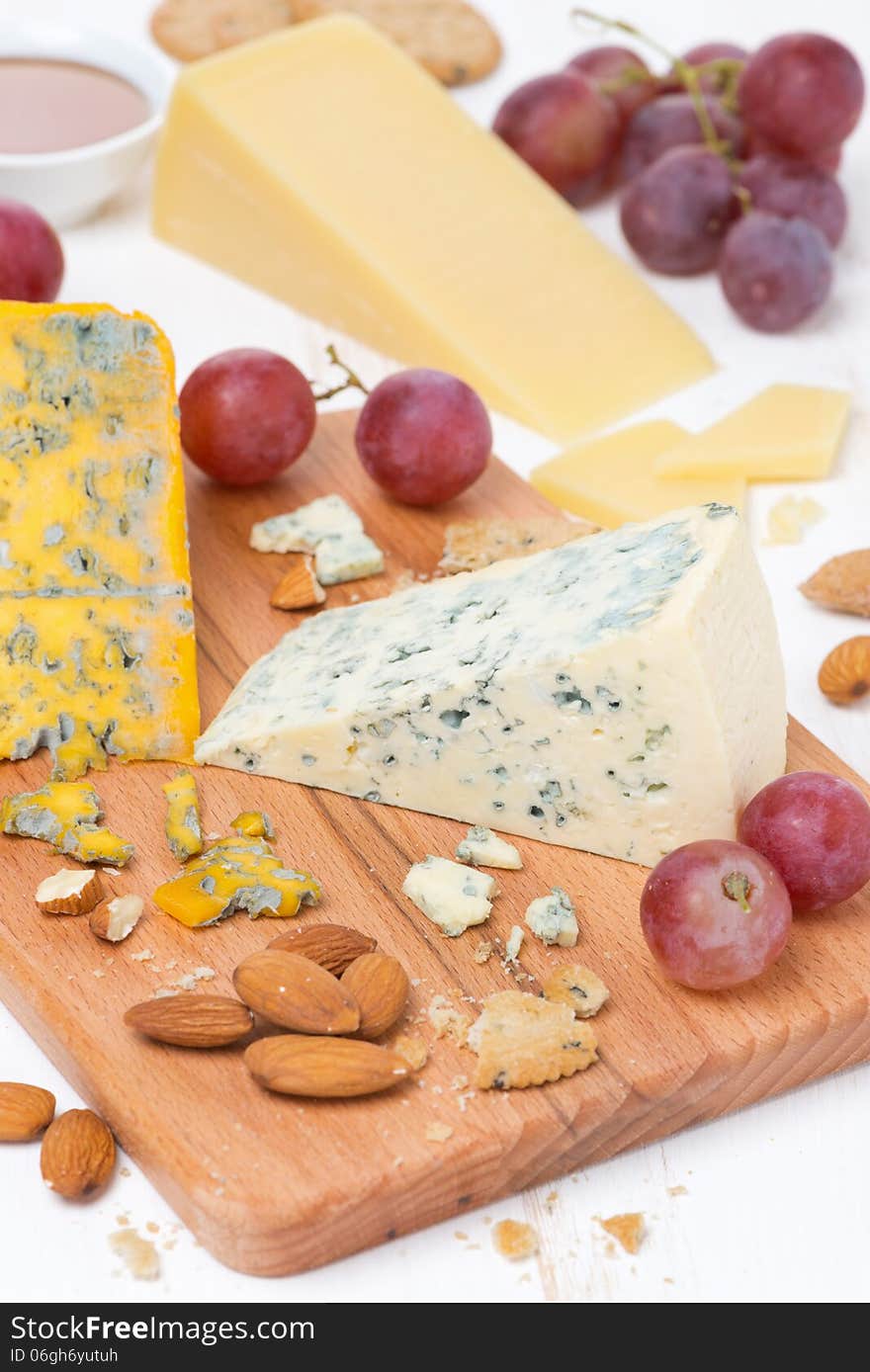 Assorted cheeses, grapes and nuts on a wooden board, close-up