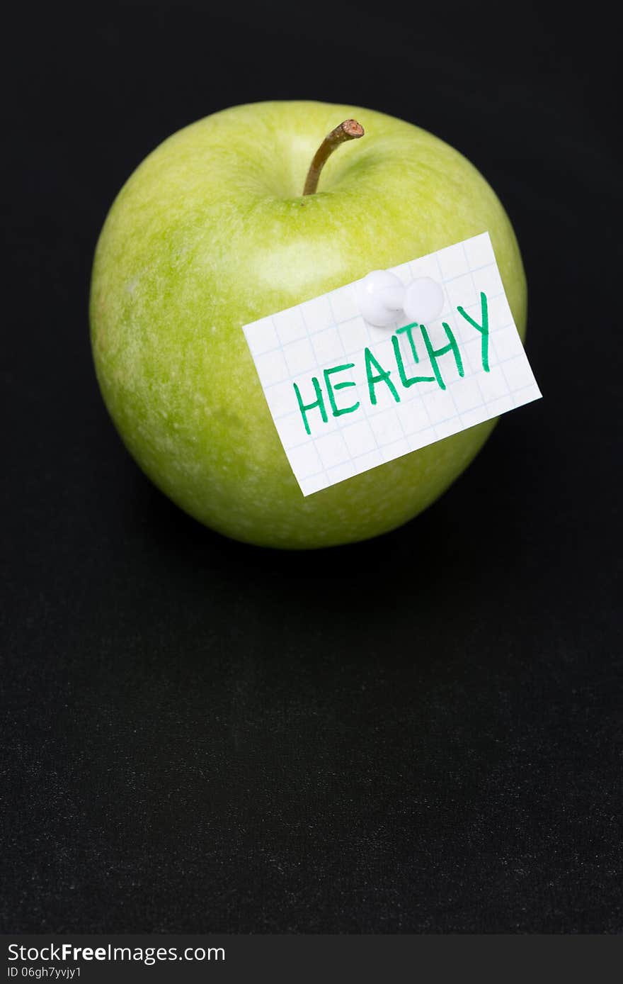 Green apple with label on a dark background, close-up