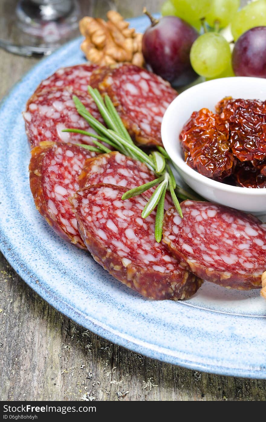 Snacks on a plate - sausage, sun-dried tomatoes, nuts, fruits