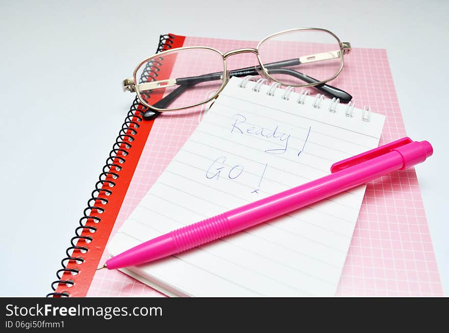 Pink pen notebook and glasses word ready