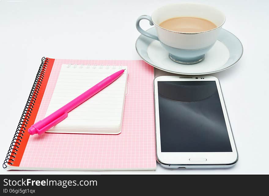 Pink Pen notebook and glasses and cup of chocolate drink on table